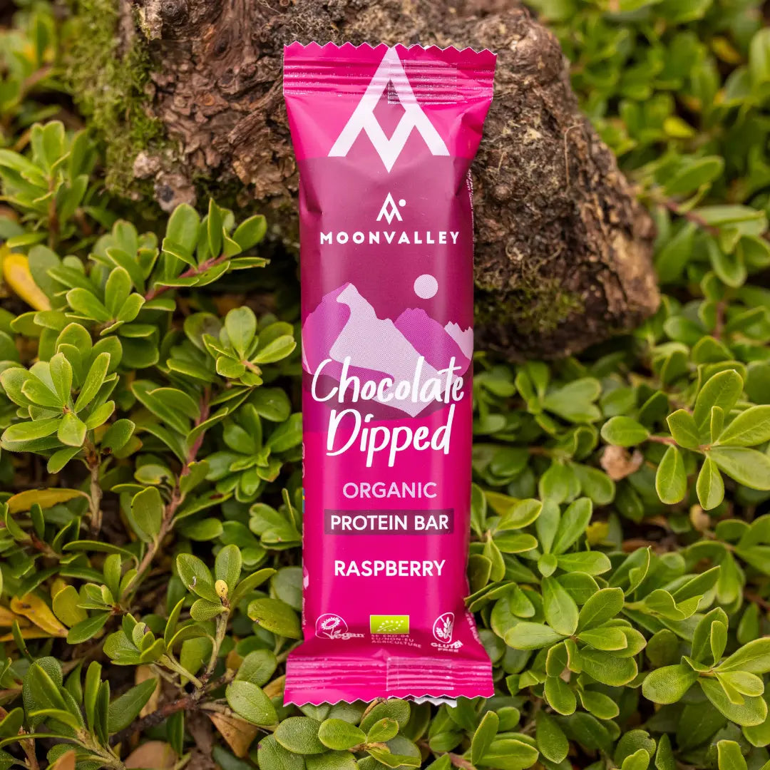 Moonvalley økologisk proteinbar med bringebær og sjokoladetrekk, fotografert i naturlige omgivelser.