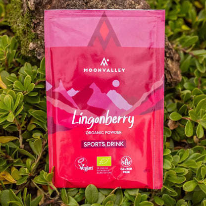 Moonvalley økologisk sportsdrikk med smak av tyttebær i pulverform, fotografert i naturlige omgivelser.